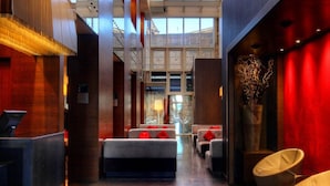 Um hall de hotel moderno com tetos altos, grandes janelas e áreas de estar.