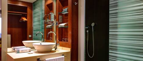 A modern bathroom with a large mirror, two sinks, a shower, and a glass partition.