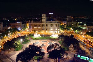 A nighttime cityscape with a prominent building featuring a central fountain and surrounding greenery. - Olivia Plaza Hotel (Barcelona)