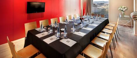 A conference room with a long table, chairs, and a TV on the wall.