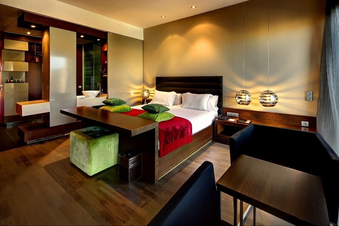 Una habitación de hotel moderna con una cama grande, un escritorio y una zona de estar.