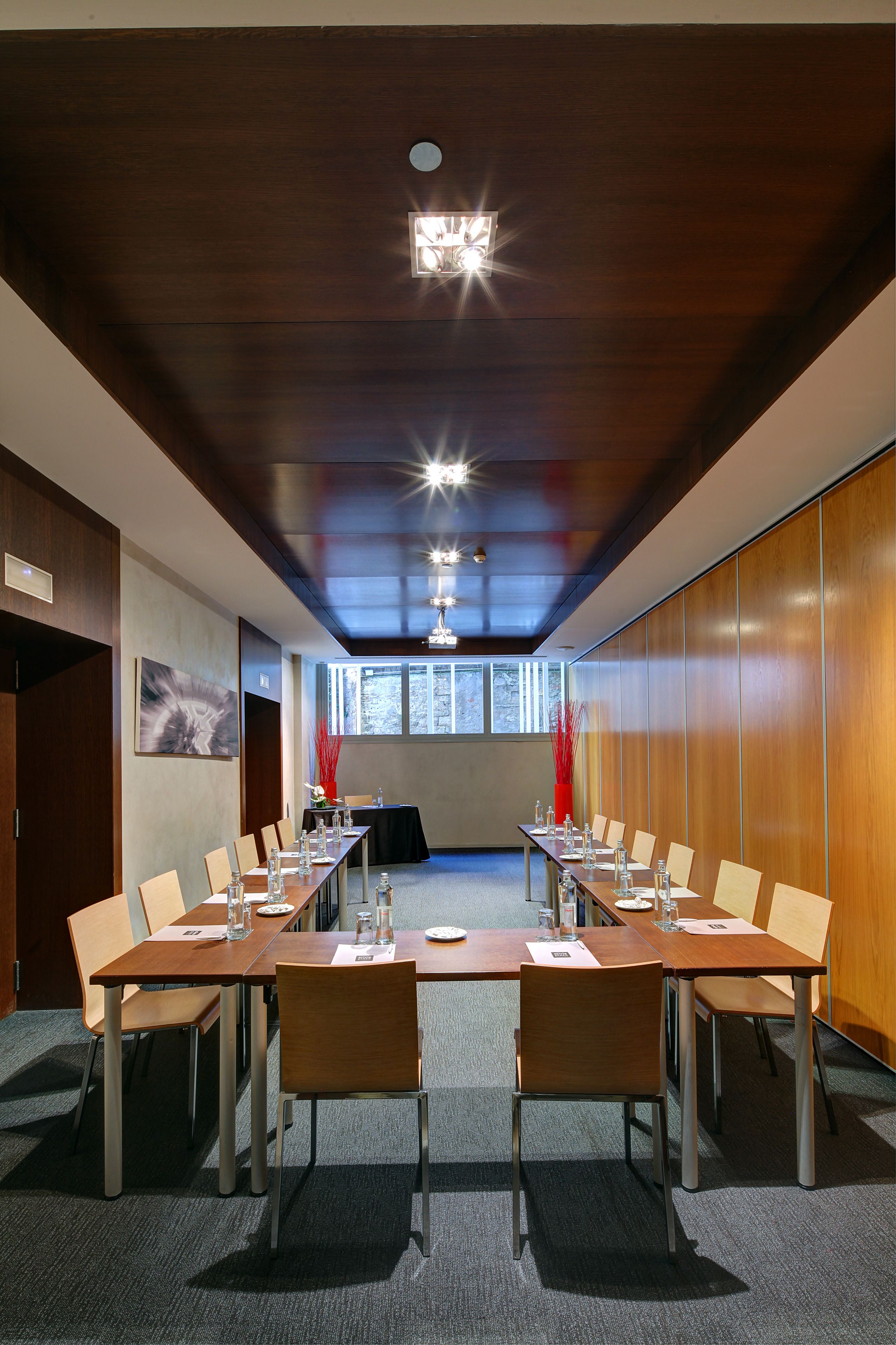 Uma sala de conferência com uma mesa comprida, cadeiras e um painel de parede de madeira.