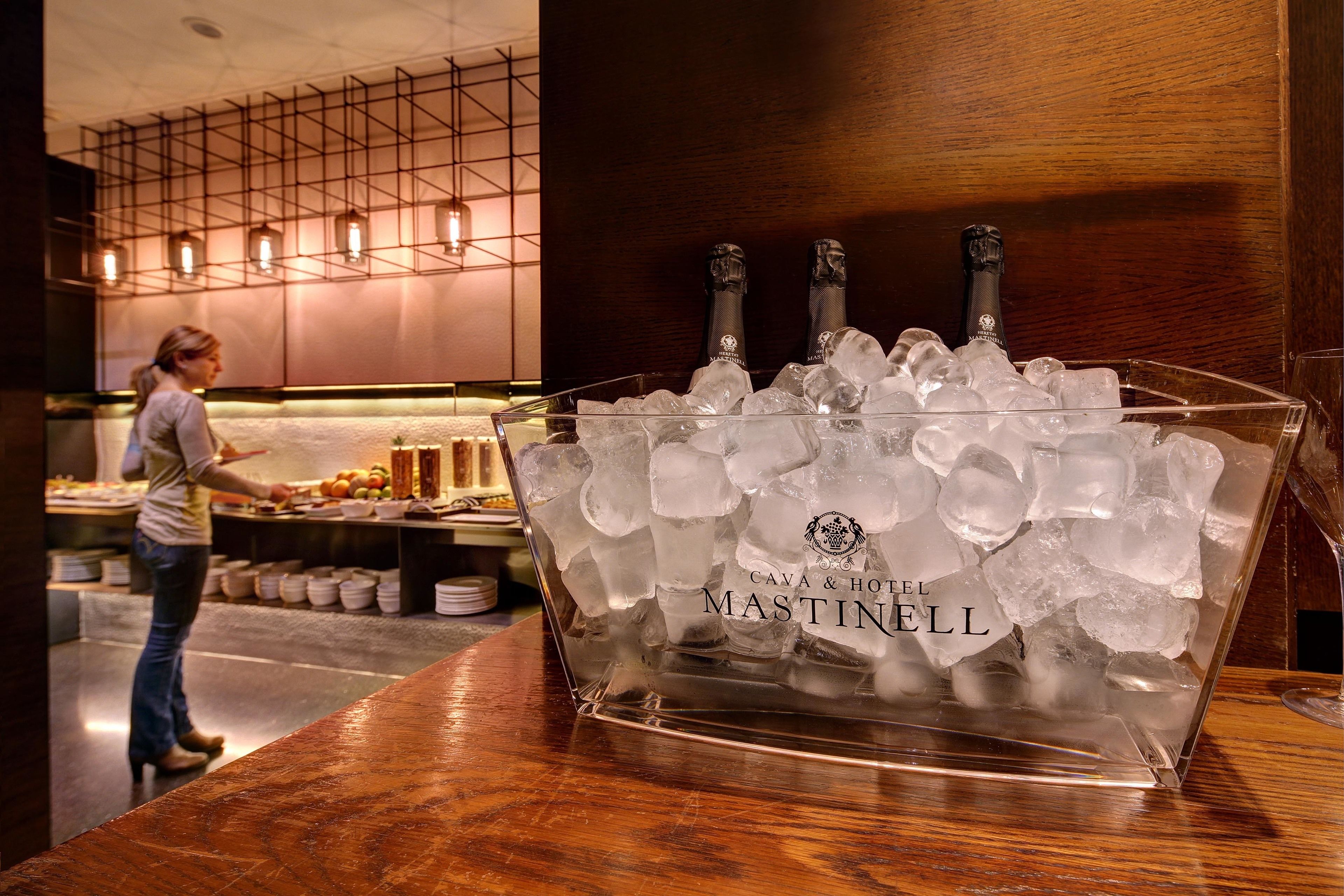 A bar area with a large ice bucket labeled "CAVA & HOTEL MASTINELL" containing bottles and ice.