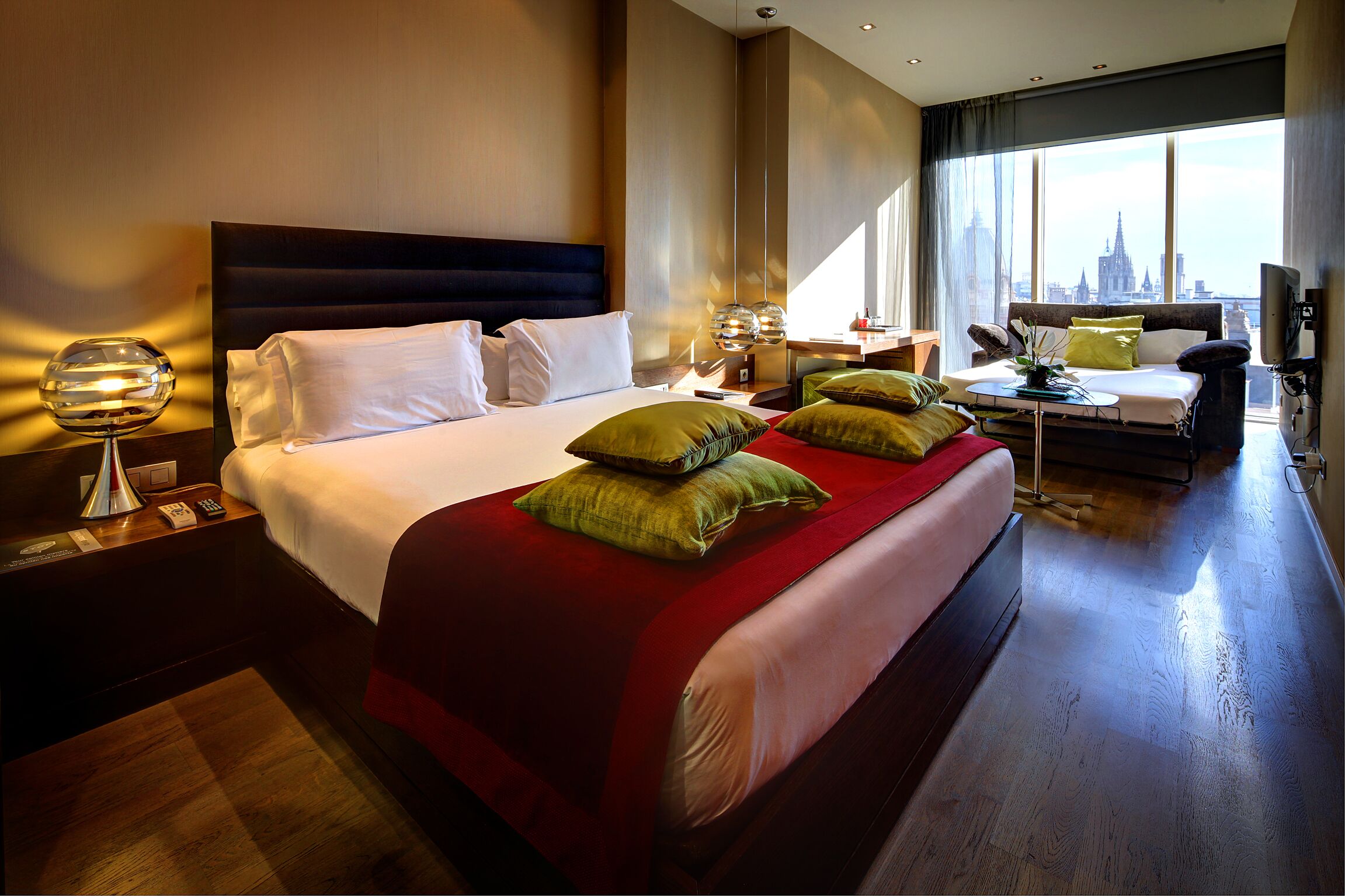 Ett hotellrum med en stor säng, ett skrivbord och utsikt över stadens silhuett.