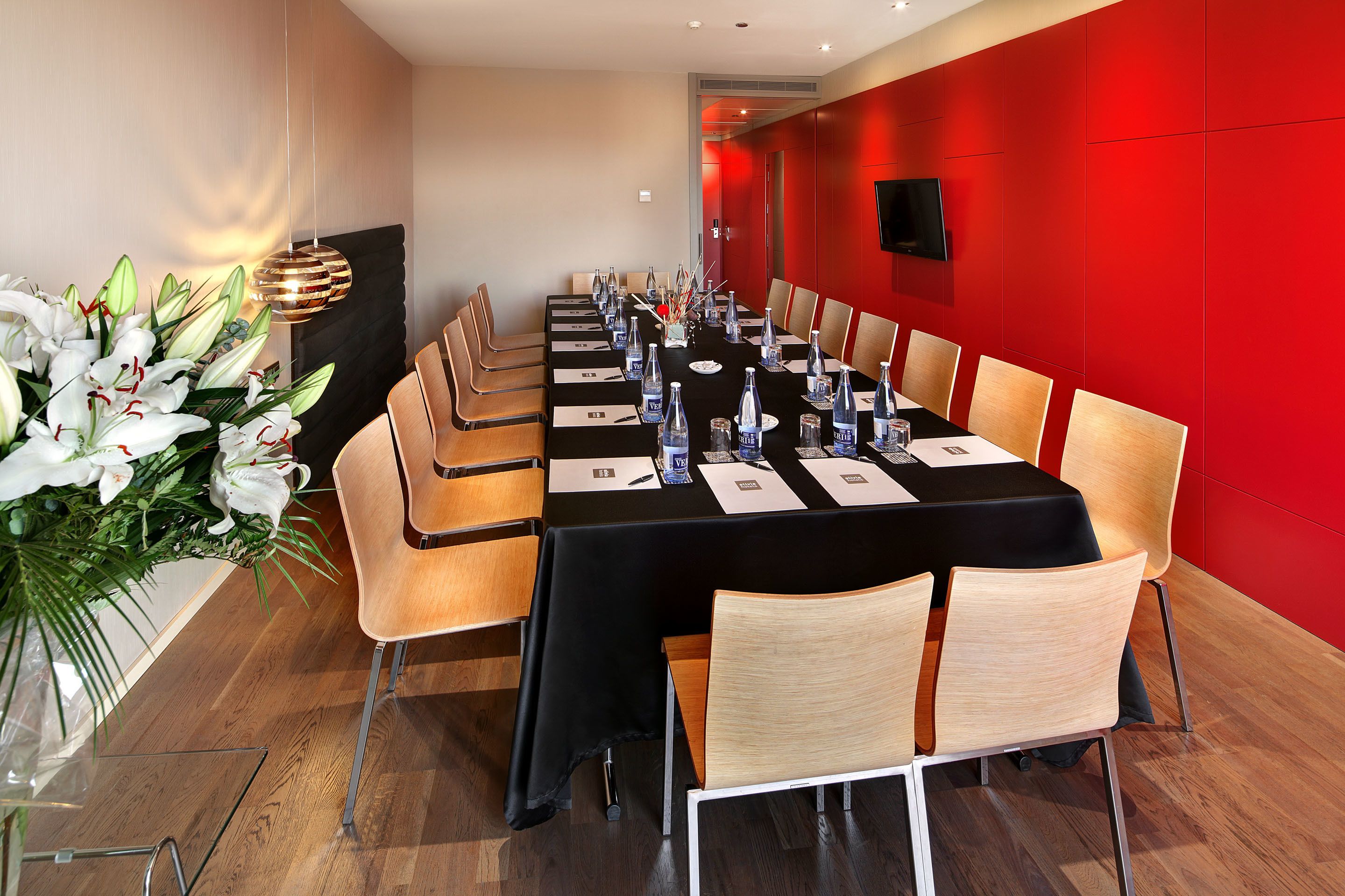 A conference room with a long table, chairs, and a large floral arrangement.