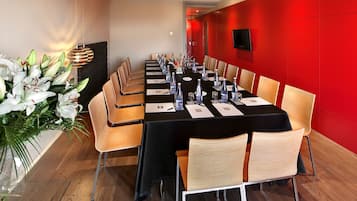 A conference room with a long table, chairs, and a large floral arrangement.