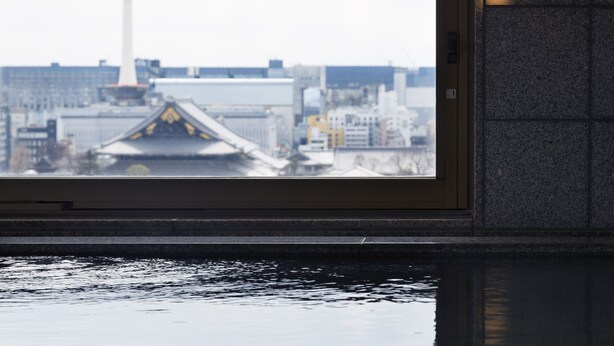Blick durch ein Fenster, mit Spiegelung eines Gebäudes und eines Turms.