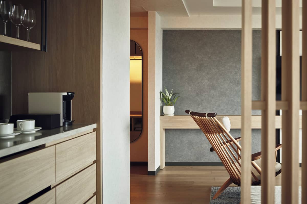Une cuisine moderne avec des meubles en bois, une machine à café et un coin repas comprenant une chaise en bois et une petite table.