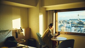 Ein Hotelzimmer mit einem Bett, einem Schreibtisch und einem Fenster mit Blick auf die Stadt.