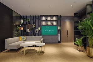 Relax in this stylish living room with a comfortable sofa, dining tables, and shelving featuring decorative items.