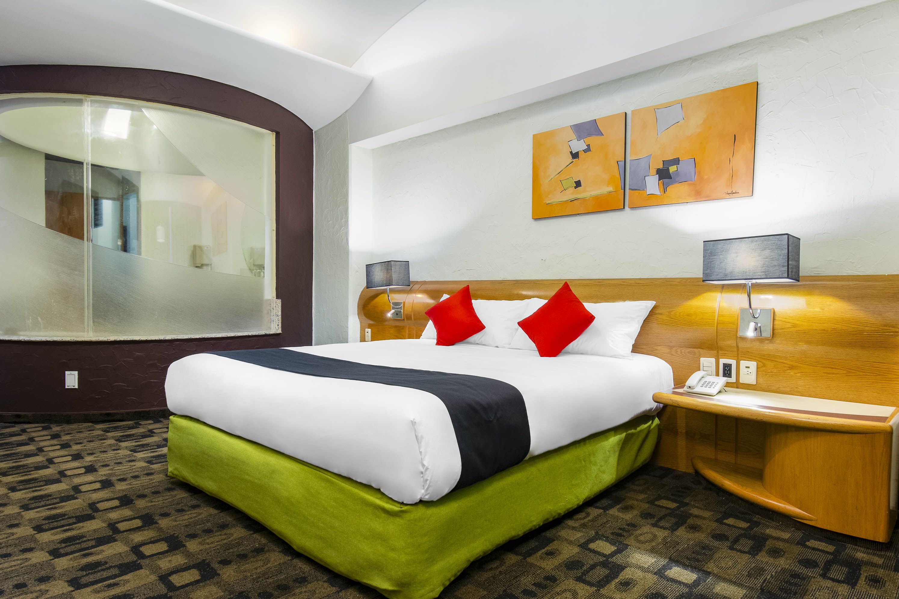 A hotel room with a large bed, a wooden headboard, two bedside lamps, and a telephone on the nightstand.
