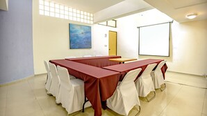 A conference room with a long table, white chairs, a painting on the wall, and a projector screen. - Mandarin Carton (Tlalnepantla de Baz)