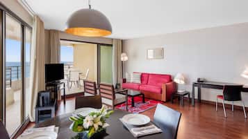 Une chambre d’hôtel moderne avec un coin repas, un canapé rouge, un bureau et un téléviseur.