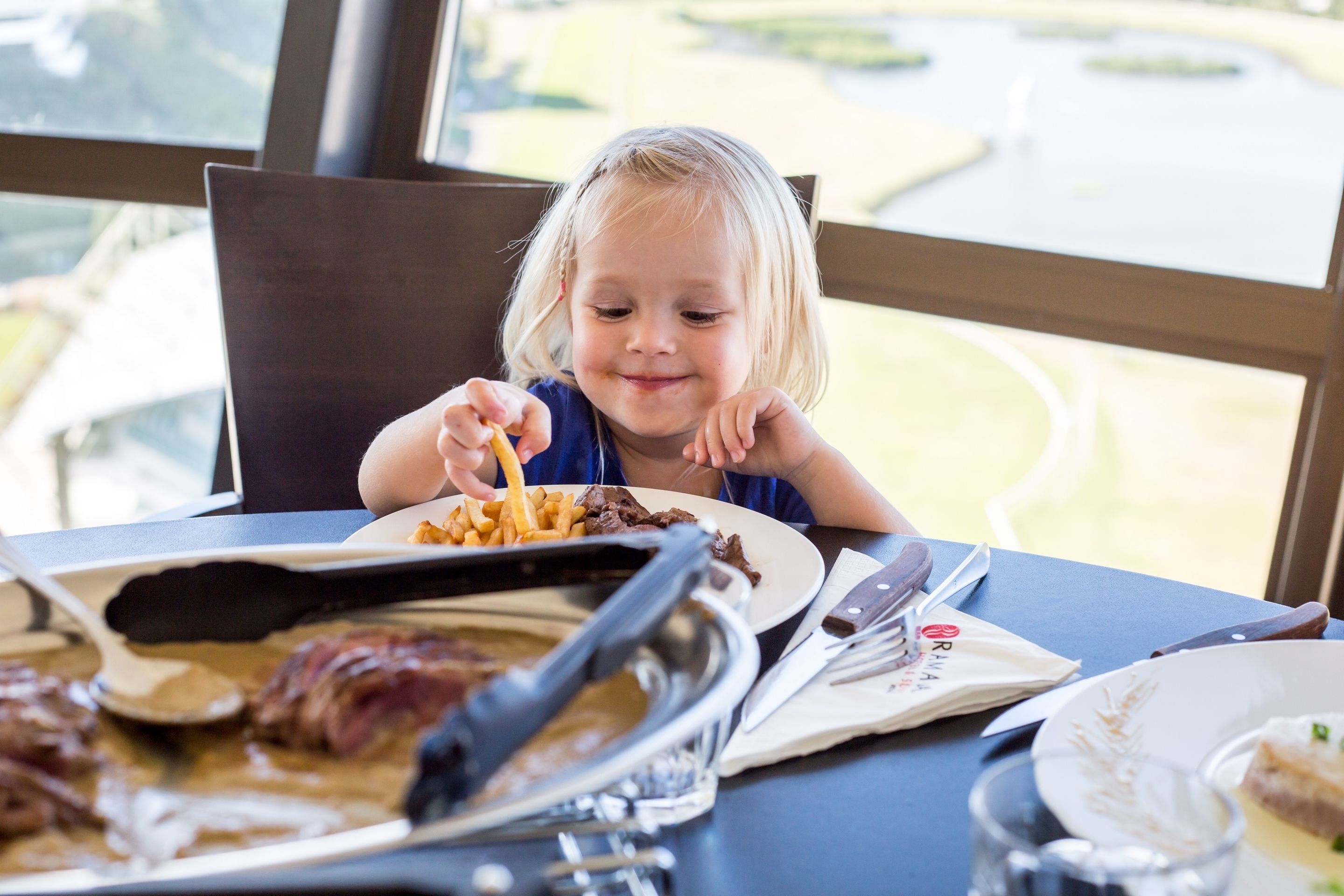 A dining table with a plate of food, a knife, and a glass.