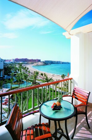 A balcony with a glass table, wooden chairs, and a view of the beach and ocean. - Shangri-La Barr Al Jissah, Muscat (Muscat)