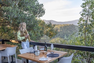 Comedor con una mesa lista para dos personas, con vista a un paisaje montañoso.