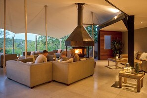 A modern living room with a large sofa set, a fireplace, and a view of the outdoors. - Hog Hollow Country Lodge (The Crags)