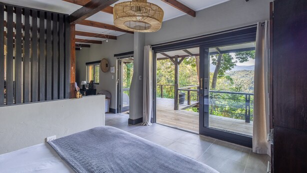 Une chambre à coucher moderne avec un grand lit, un plafond en bois et un balcon offrant une vue sur l’extérieur.