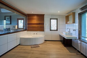 Un baño moderno con una bañera independiente, un espejo grande y un ventanal que proporciona luz natural.