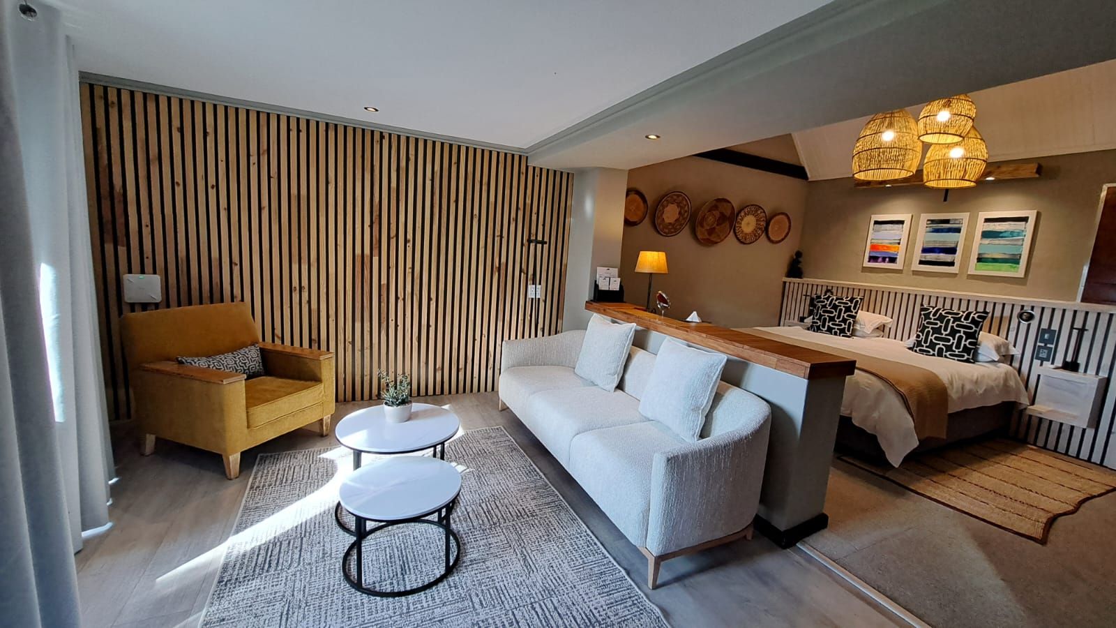 Una sala de estar moderna con un sofá, sillón, mesa de centro y una pequeña zona de comedor con un banco.
