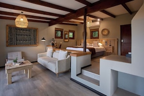 A modern living room with a sofa, a coffee table, and a dining area with a bench. There are two pendant lights hanging from the ceiling. - Hog Hollow Country Lodge (The Crags)