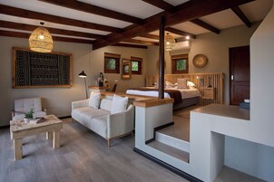 Una sala moderna con un sofá, una mesa de centro y un comedor con un banco. Hay dos lámparas colgantes en el techo.