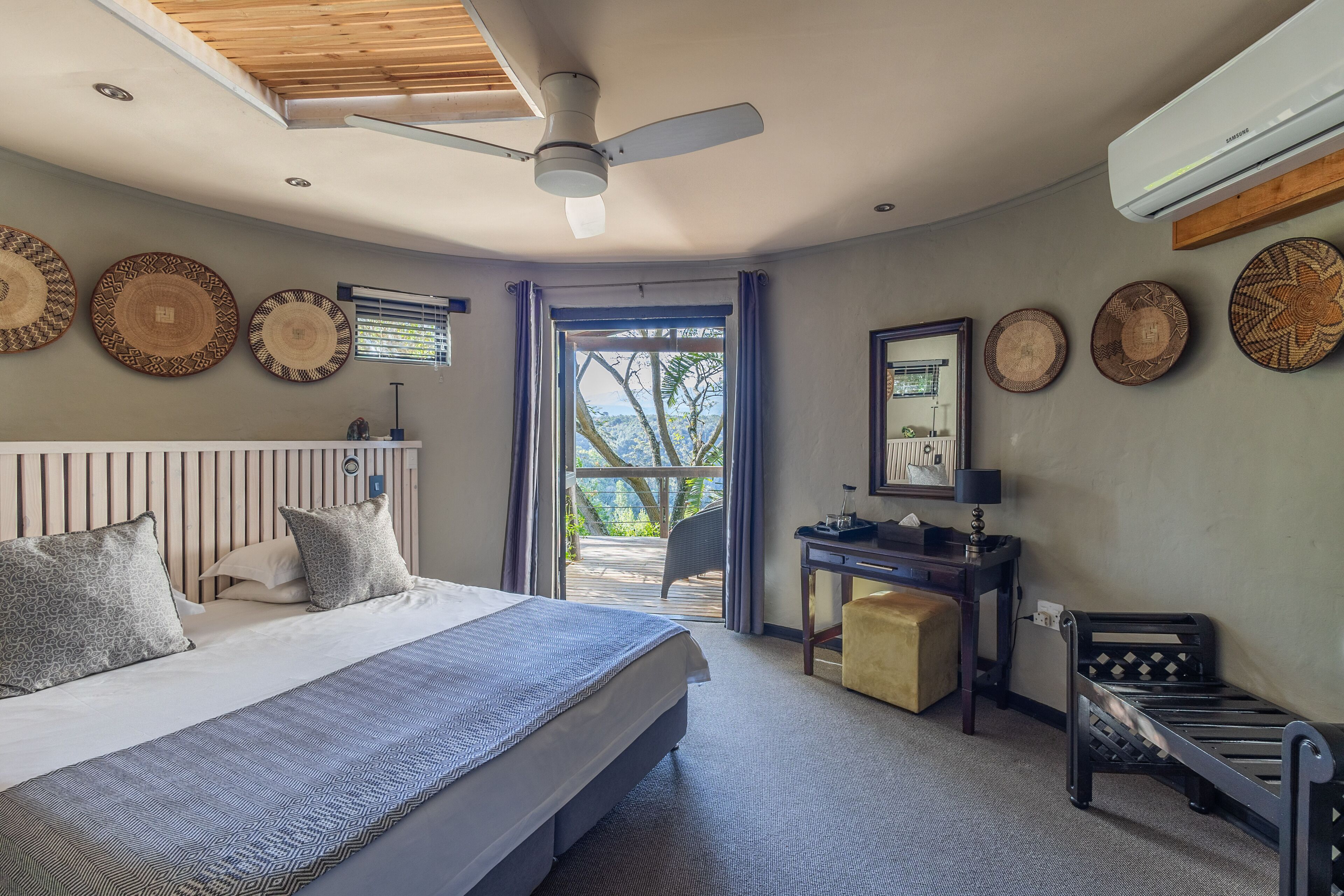 A bedroom with a bed, a desk, a chair, and a small bench.