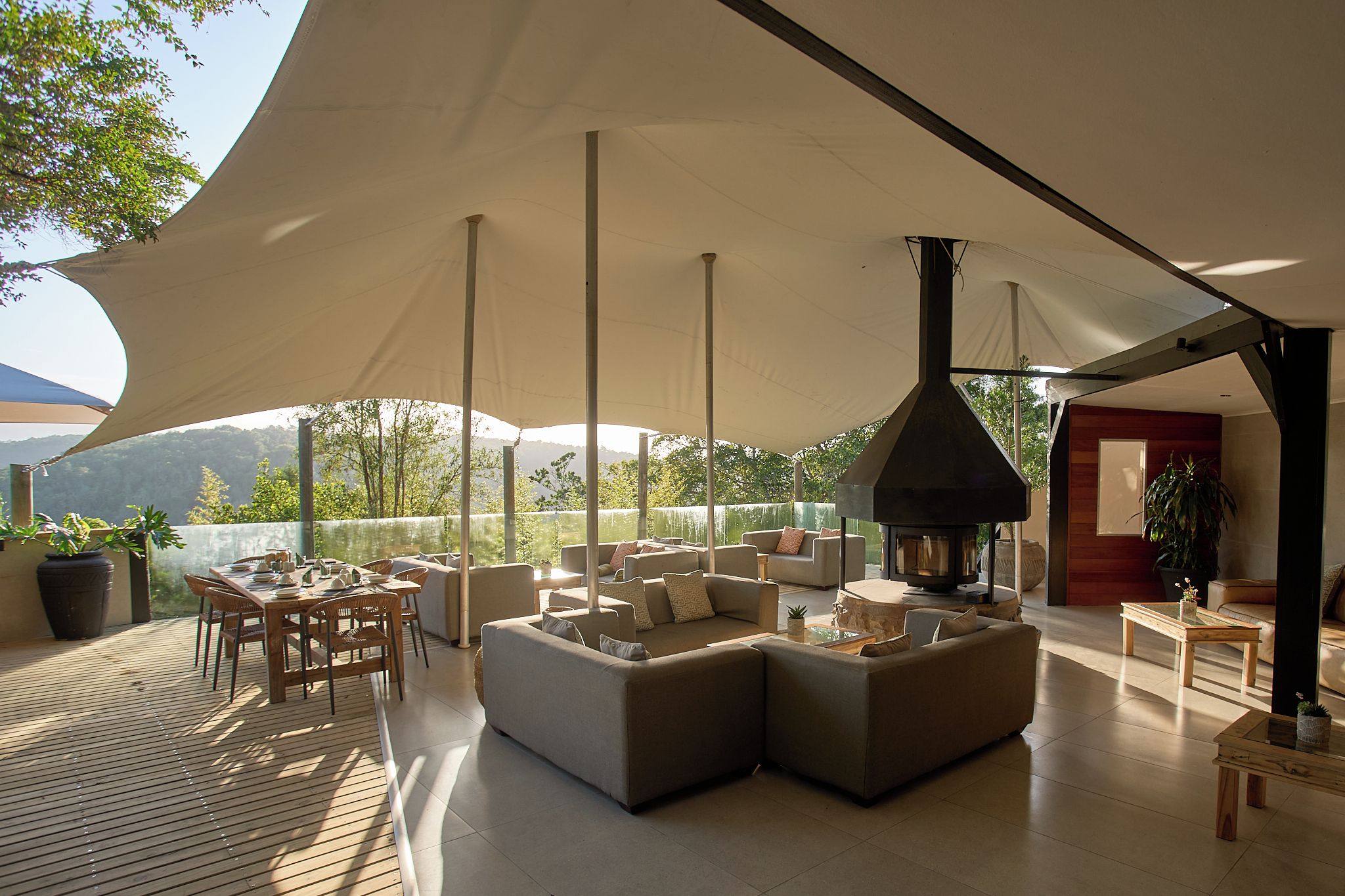 An outdoor lounge area with a large umbrella, seating, and a wood-burning stove.