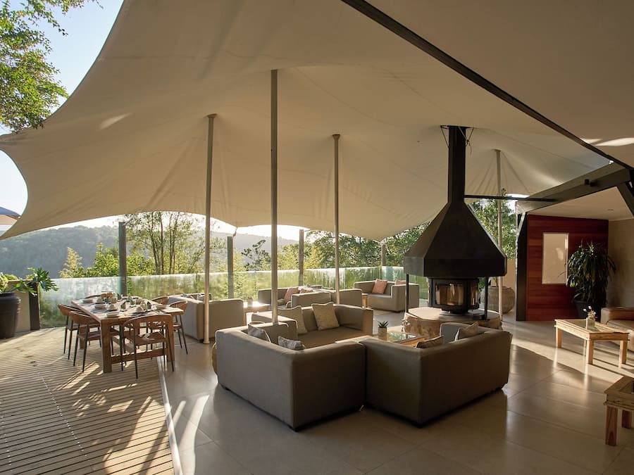 An outdoor lounge area with a large umbrella, seating, and a wood-burning stove.