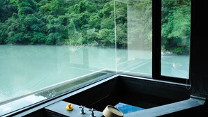 A modern bathroom with a large window, a bathtub, a sink, and a toilet. - Volando Urai Spring Spa and Resort (New Taipei City)