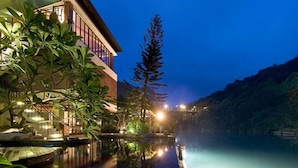 A modern hotel with a pool, surrounded by lush greenery and a mountain backdrop. - Volando Urai Spring Spa and Resort (New Taipei City)