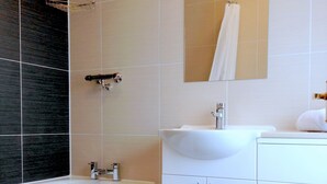 A modern bathroom with a bathtub, sink, and toilet. - Ely House Hotel (Wolverhampton)