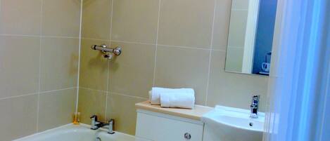 Un baño con bañera, inodoro, lavamanos y espejo.