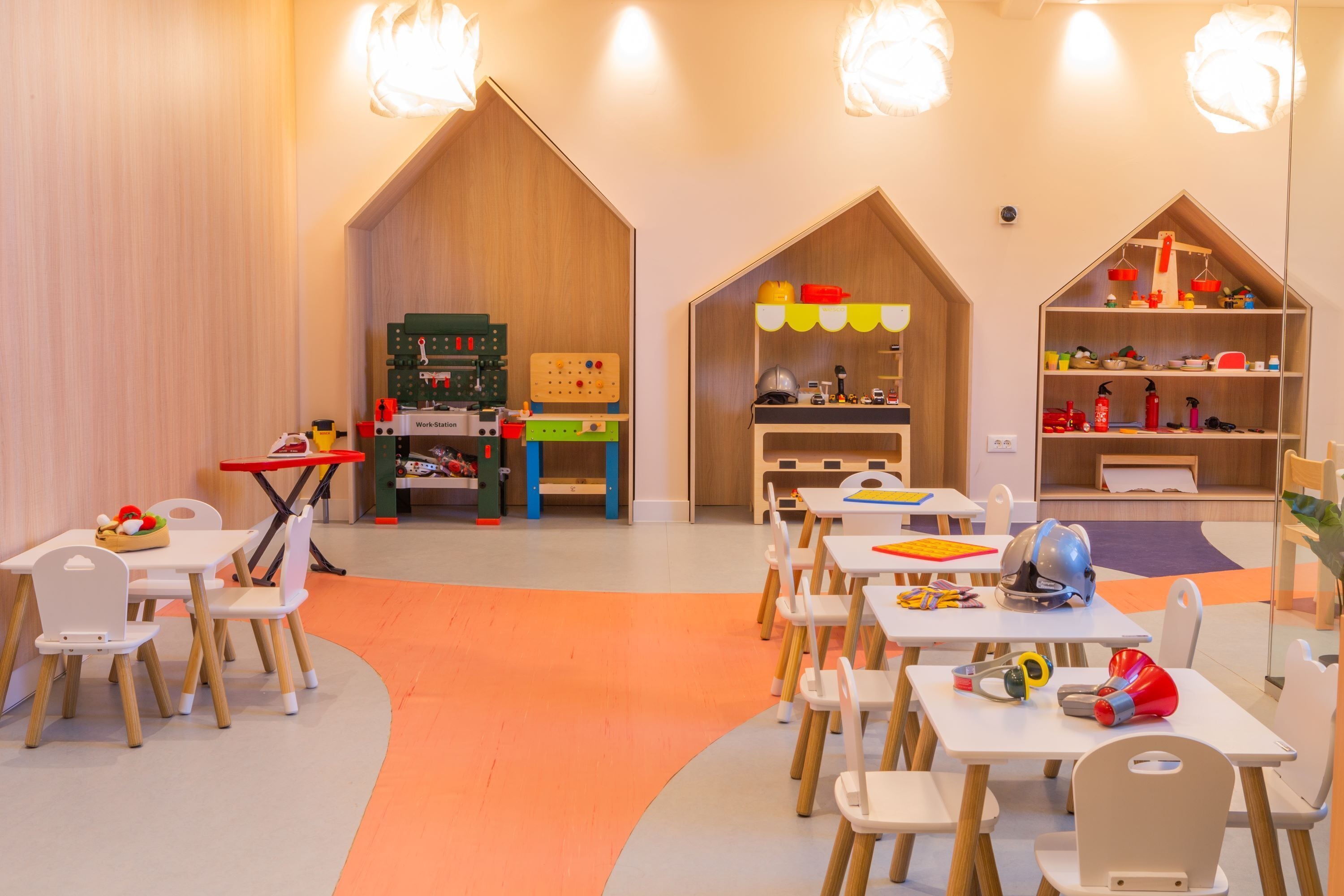 Een kinderspeelruimte met tafels, stoelen en didactisch speelgoed.