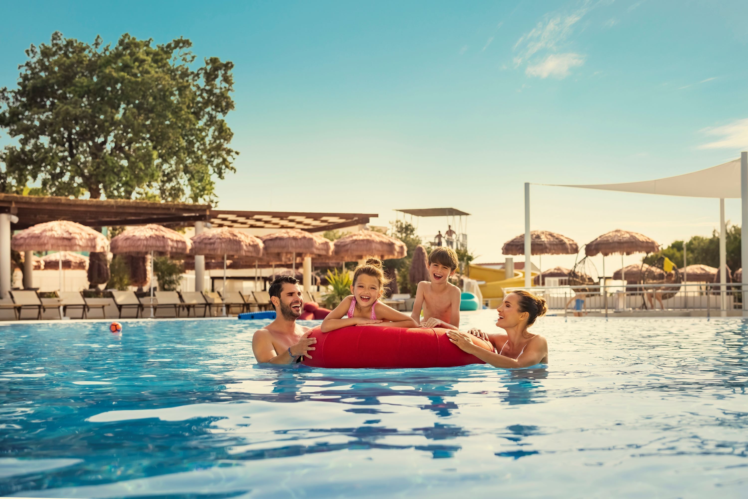 A swimming pool with lounge chairs and umbrellas in the background.