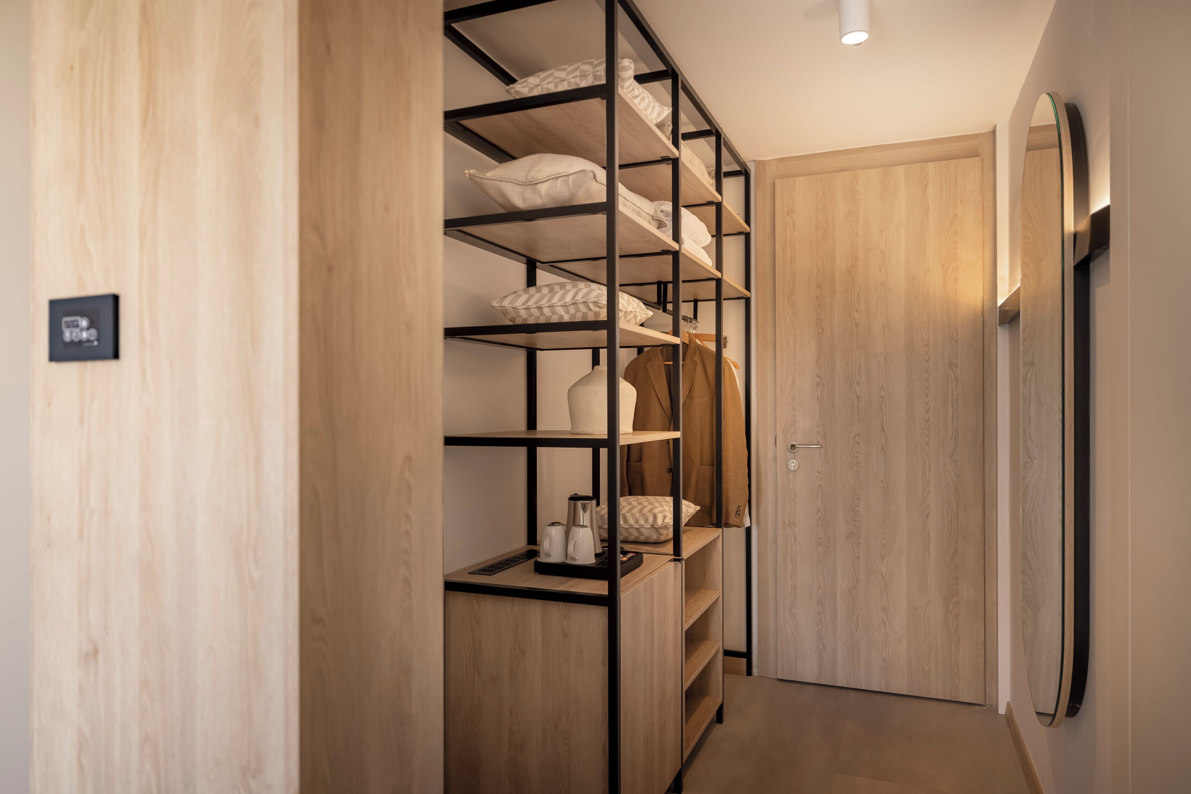A narrow hallway with a wooden wardrobe and a built-in shelving unit.