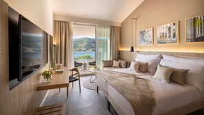 A modern hotel room with a large bed, a desk, and a view of the sea. - Valamar Tirena Hotel (Dubrovnik)