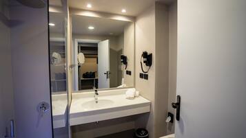 Une salle de bain moderne avec un grand miroir, un lavabo blanc et une douche.