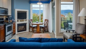 A modern kitchen with a built-in oven and microwave, a dining area with a round table and chairs, and a large window offering a scenic view. - Summerland Waterfront Resort & Spa (Summerland)