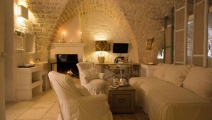 Una habitación acogedora con techo abovedado de piedra, chimenea, televisor y un rincón de estar confortable.