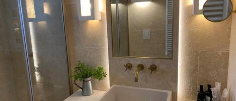 A bathroom with a large mirror, a sink, and a towel rack.
