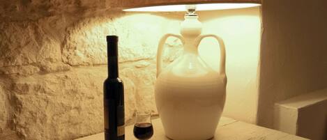 Una mesa con una botella de vino, una copa de vino y un libro abierto bajo una lámpara.
