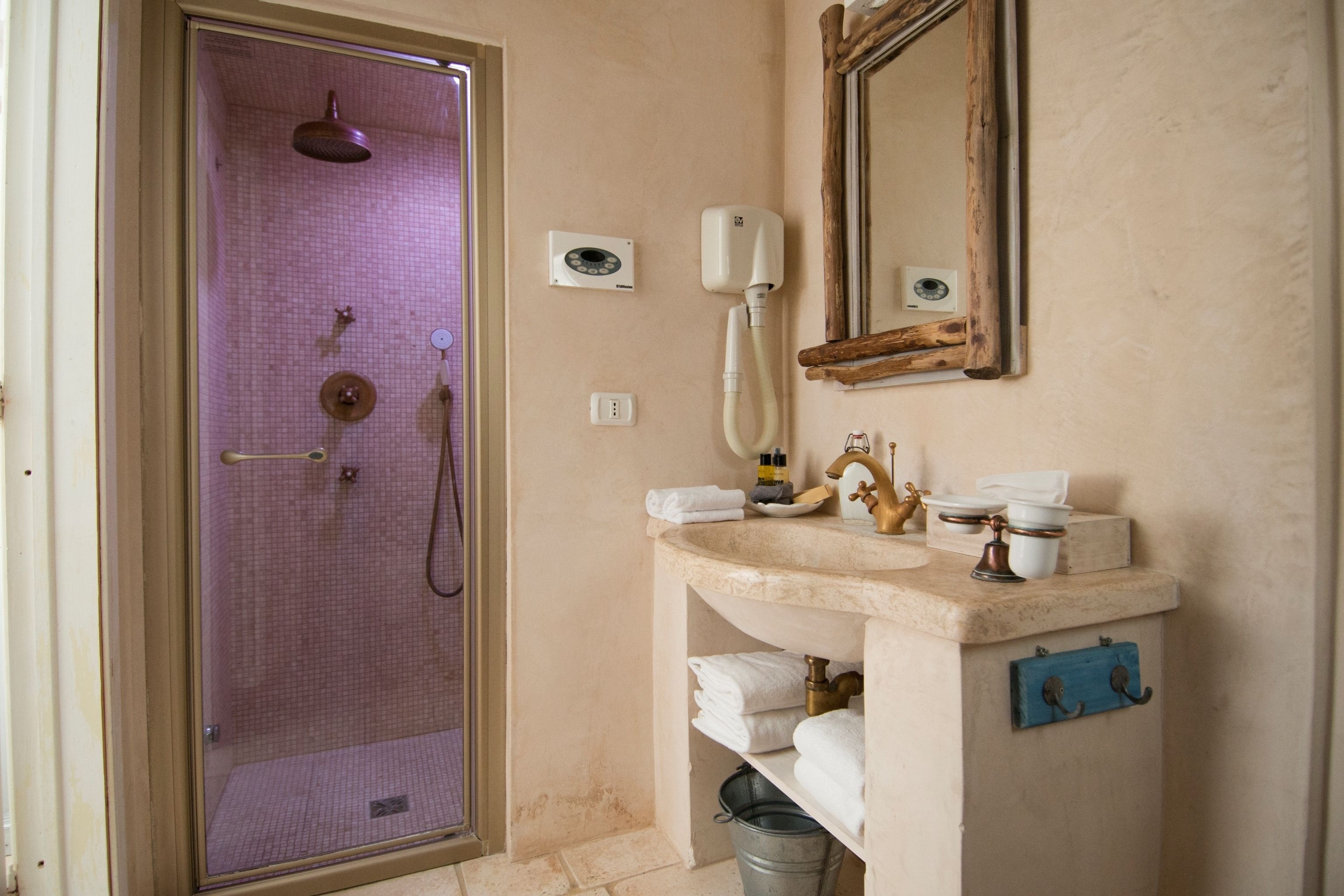 Un baño con ducha envuelta en vidrio, un lavamanos con espejo y un perchero para toallas.