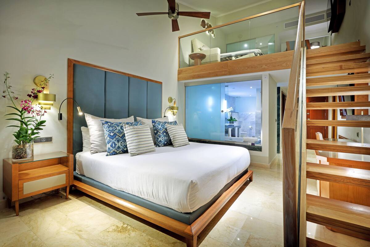 A modern bedroom with a large bed, wooden headboard, and a built-in desk.