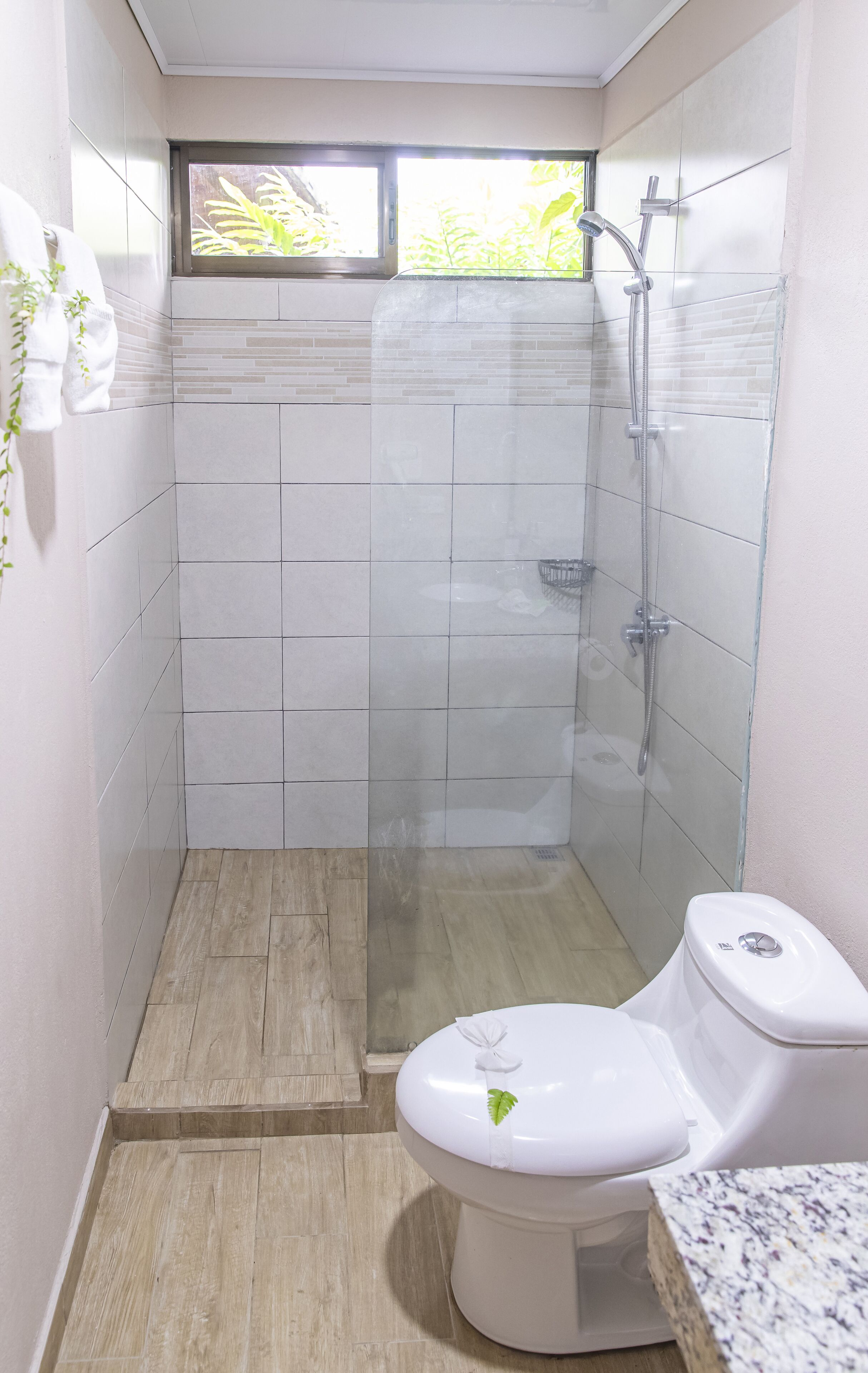 Ein kleines Badezimmer mit Dusche, Toilette und einem Fenster.
