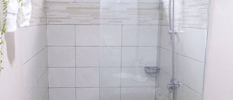 Ein kleines Badezimmer mit Dusche, Toilette und einem Fenster.