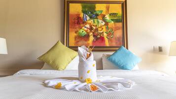 A neatly made bed with white linens, a towel with flowers, and two pillows in different colors.