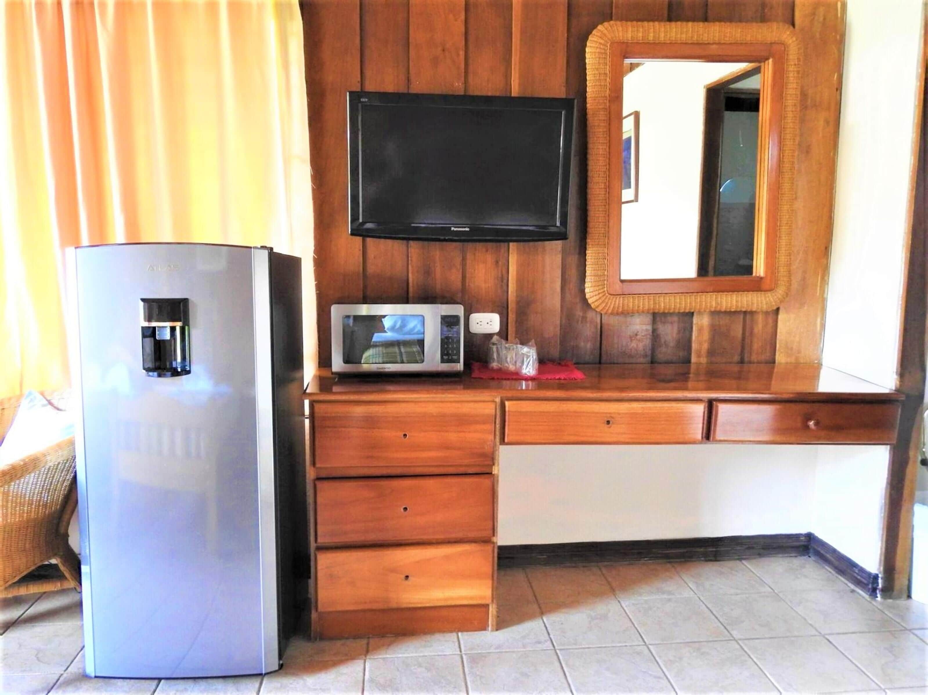 Une petite cuisine équipée comprenant un réfrigérateur, un four à micro-ondes et un plan de travail en bois.