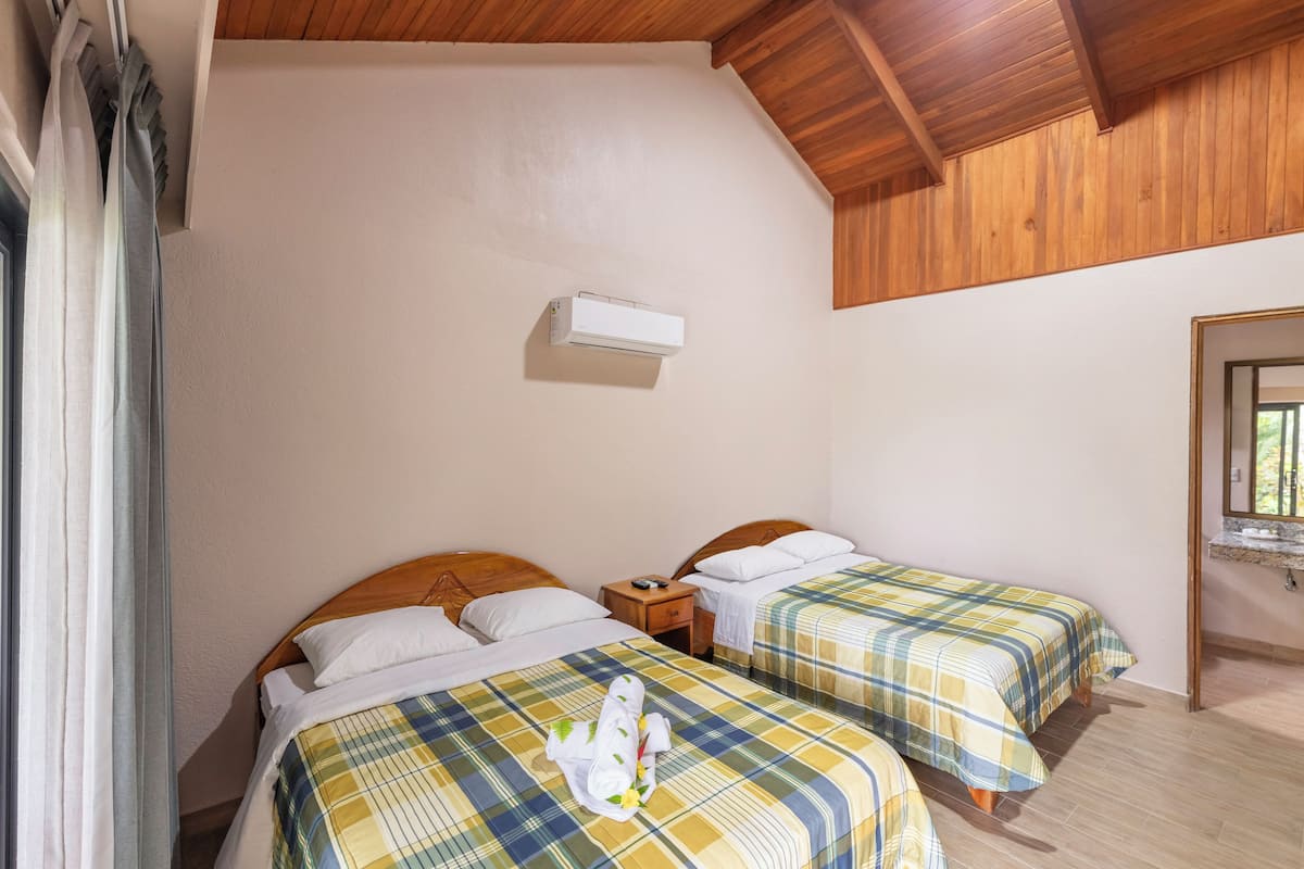 Een slaapkamer met twee bedden, een plafondventilator en een raam met gordijnen.