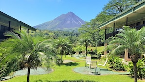 Une cour d’hôtel avec des palmiers, une vue sur une montagne et des espaces de détente en plein air.